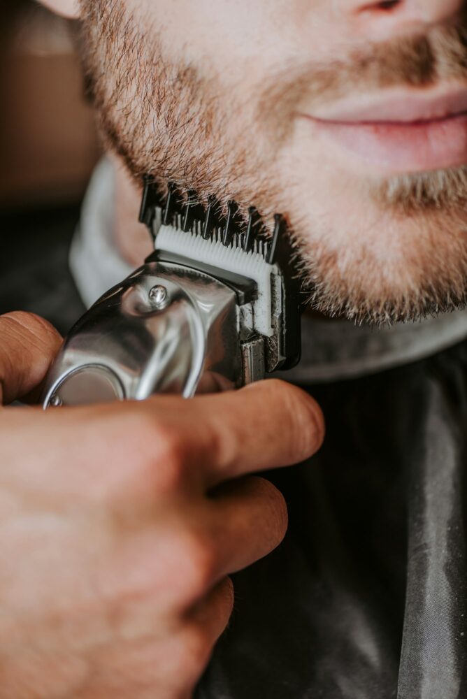 cropped view of barber holding trimmer while shaving man